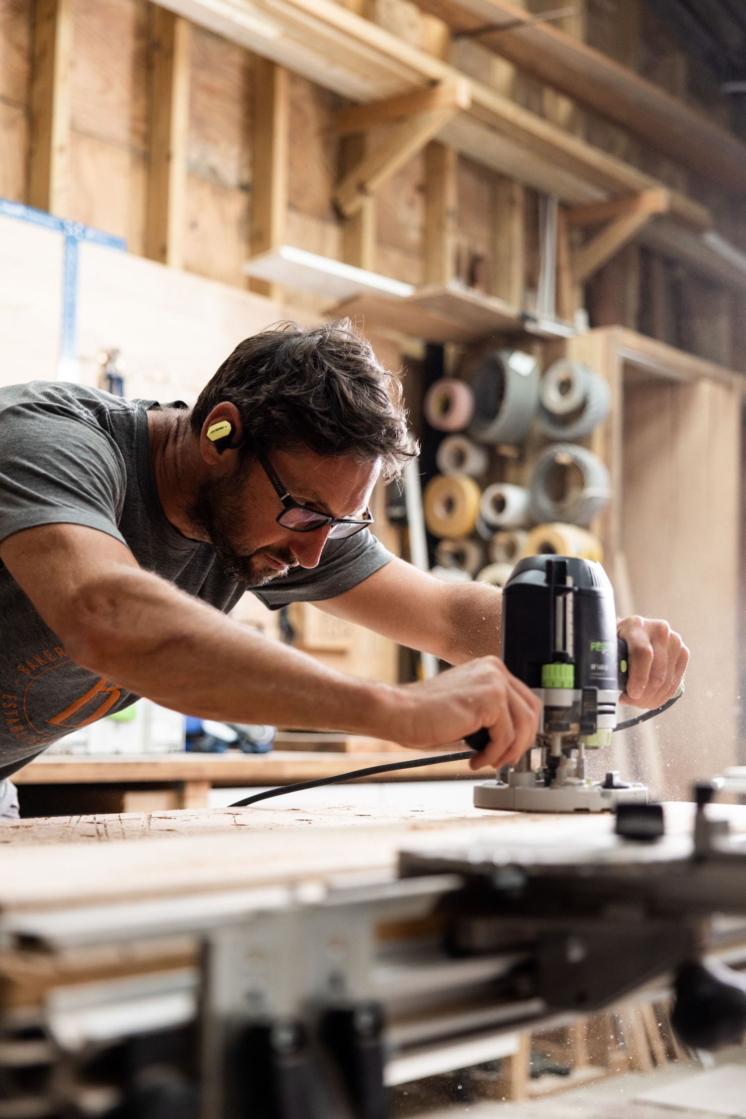 Craftsman using power tools on wooden workbench in professional workshop.