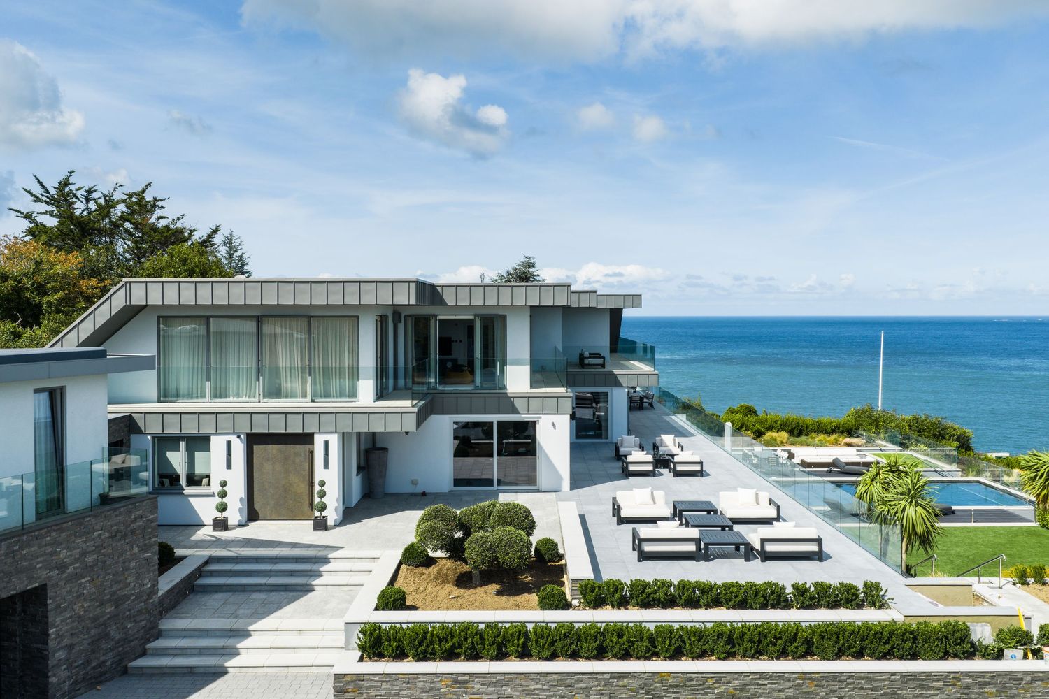 Modern luxury oceanfront villa with infinity pool and panoramic views of the blue sea and coastline.