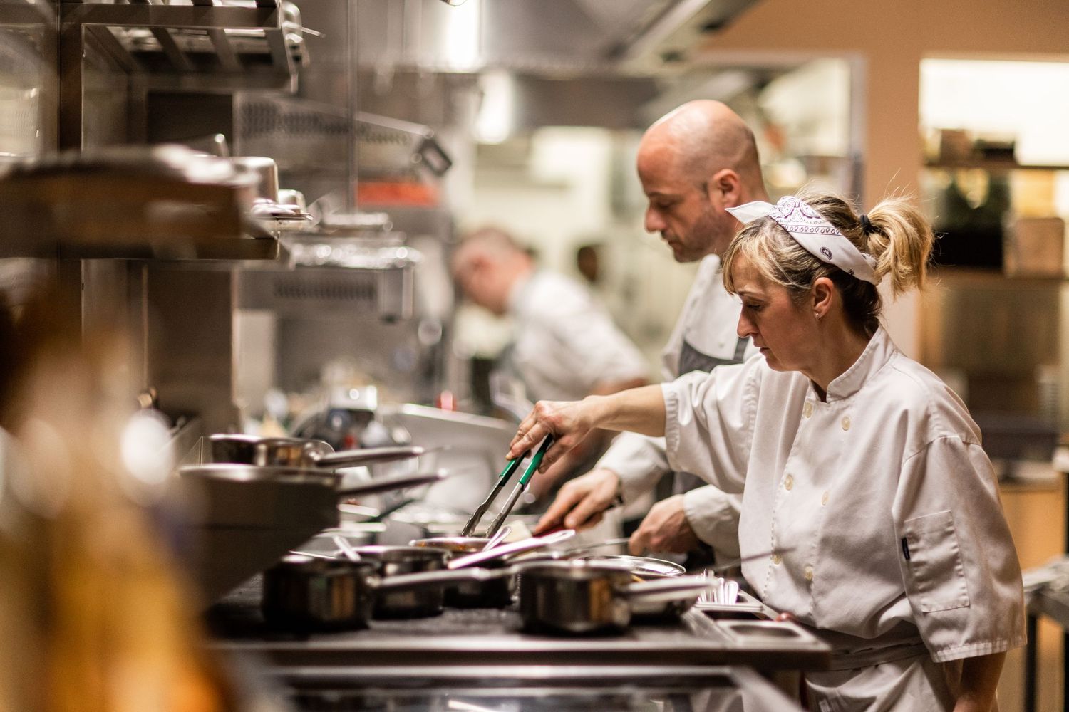 Busy restaurant kitchen staff working at food preparation stations.