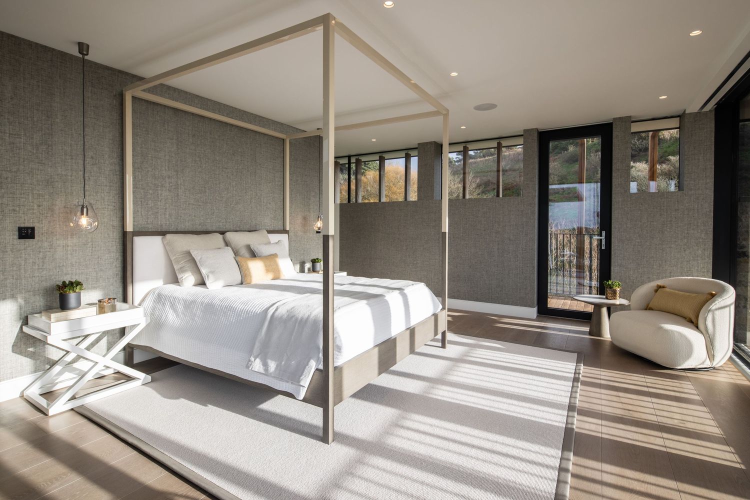 Luxurious bedroom with canopy bed, textured walls, and floor-to-ceiling windows.