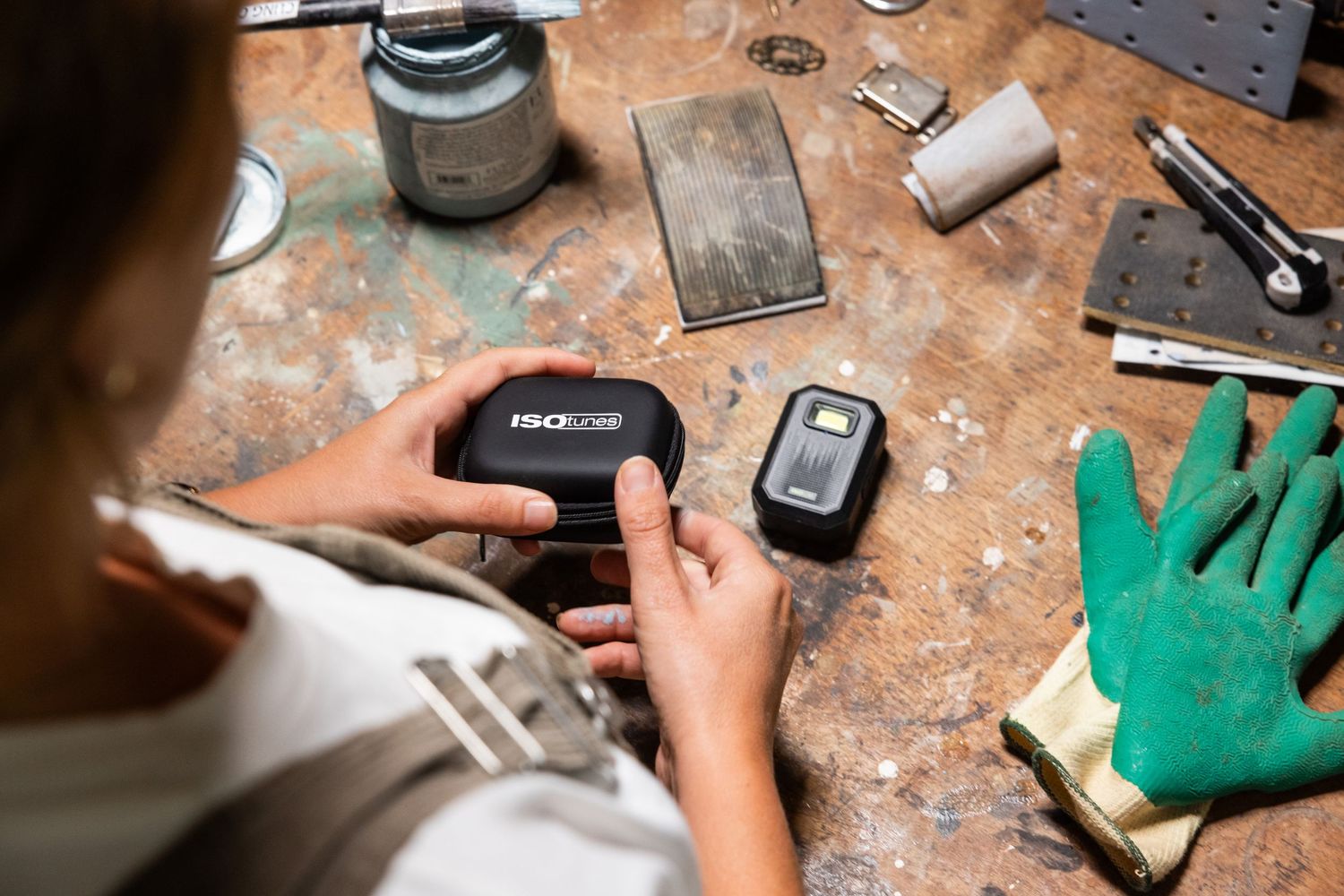Workshop table with various tools and electronic devices scattered on wooden surface.