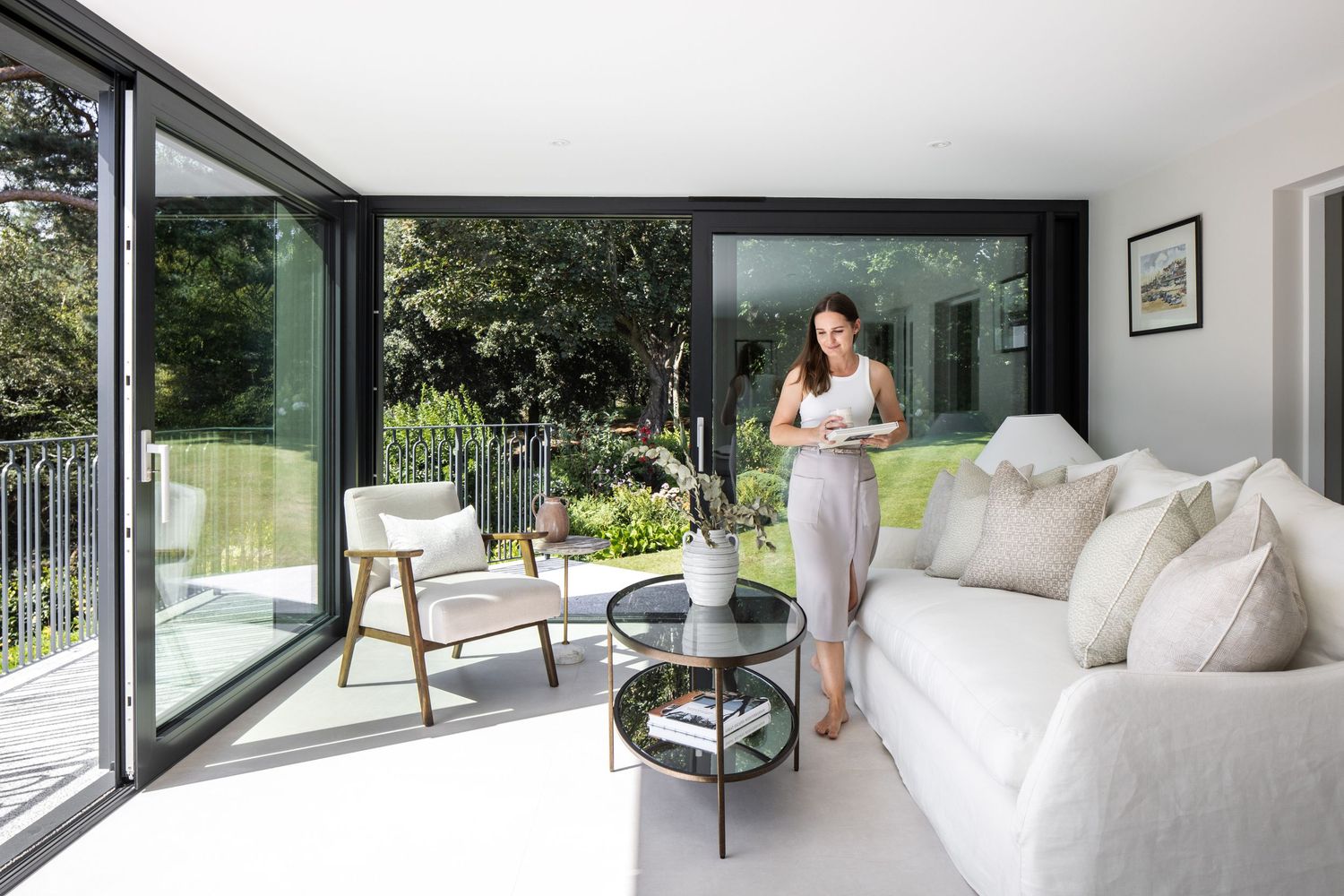 Bright modern living space with floor-to-ceiling windows overlooking a garden landscape.