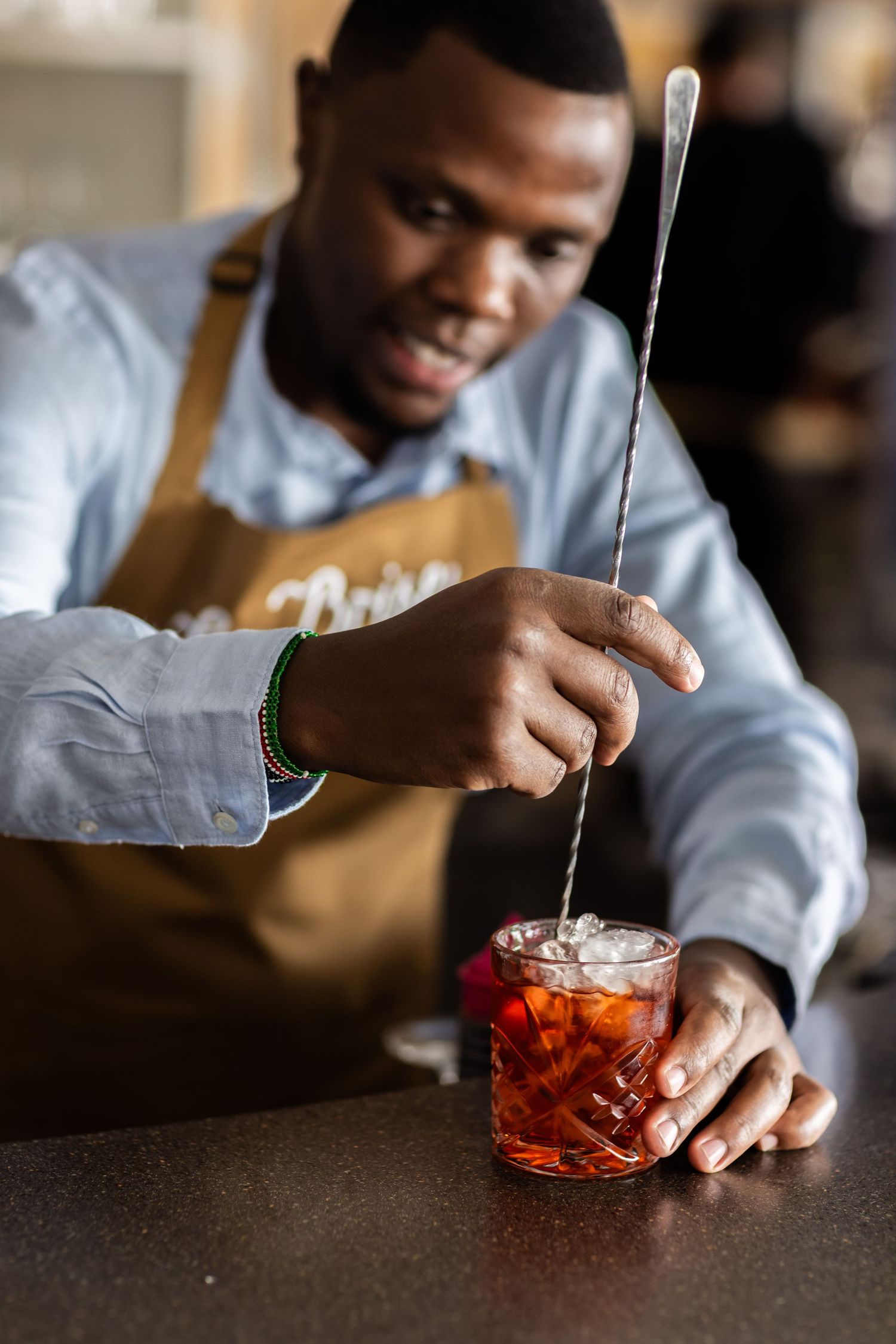 Bartender preparing a craft cocktail at a bar counter.