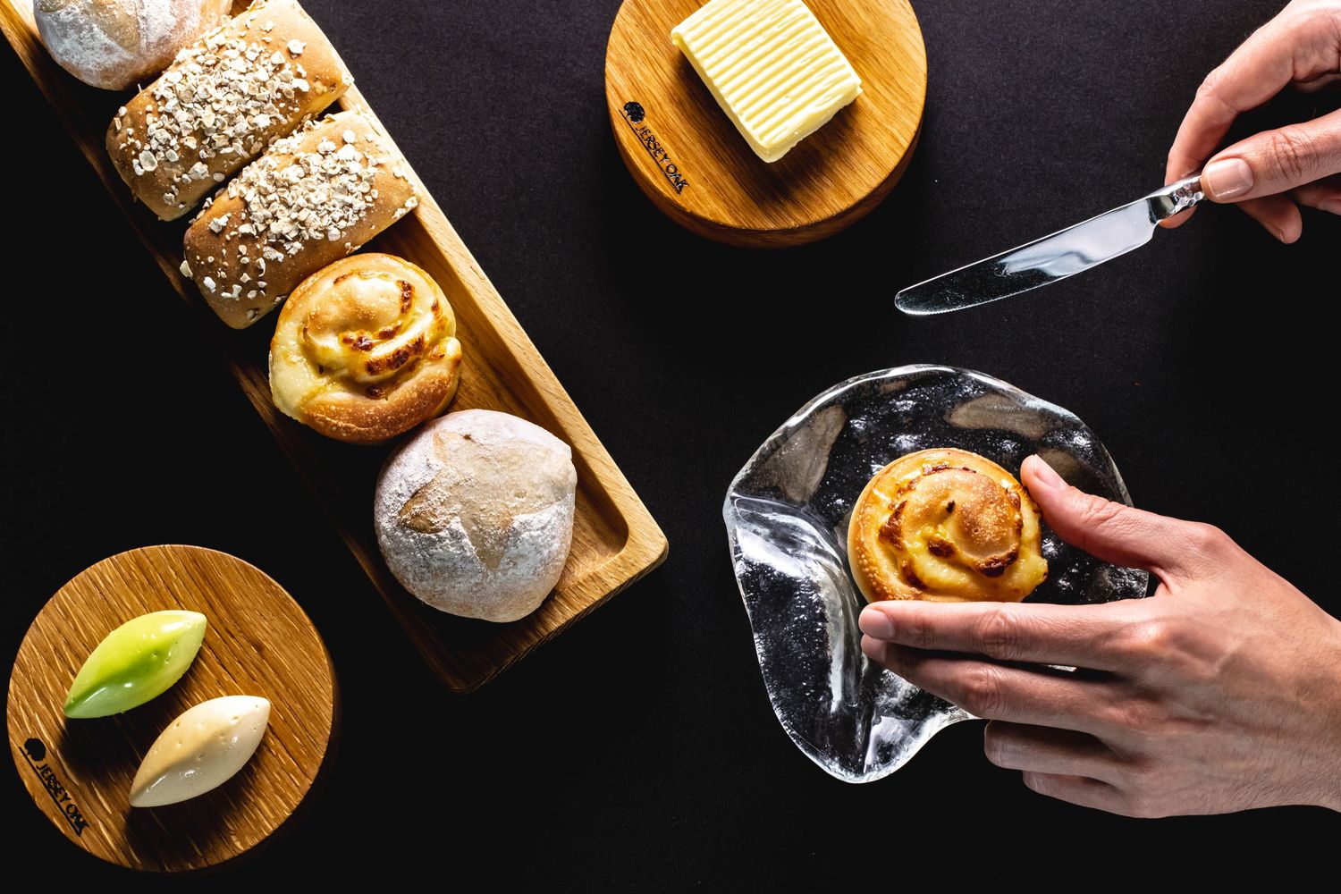 Culinary preparation with butter, bread, and utensils on dark wooden boards.