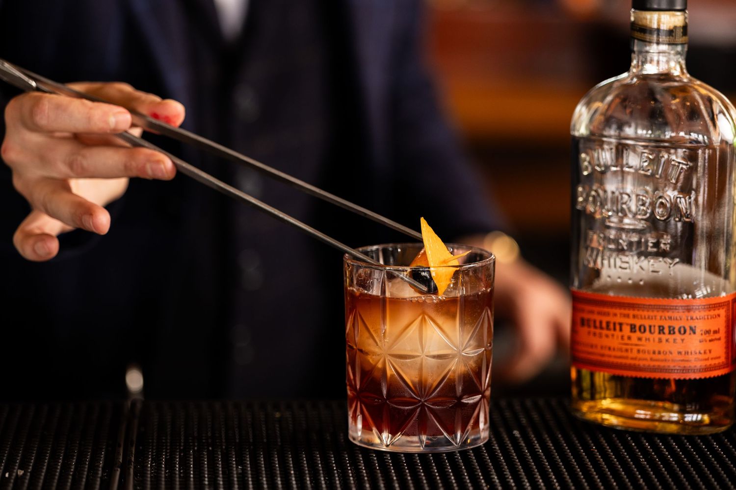 Professional bartender preparing craft cocktails with bourbon and garnishes.