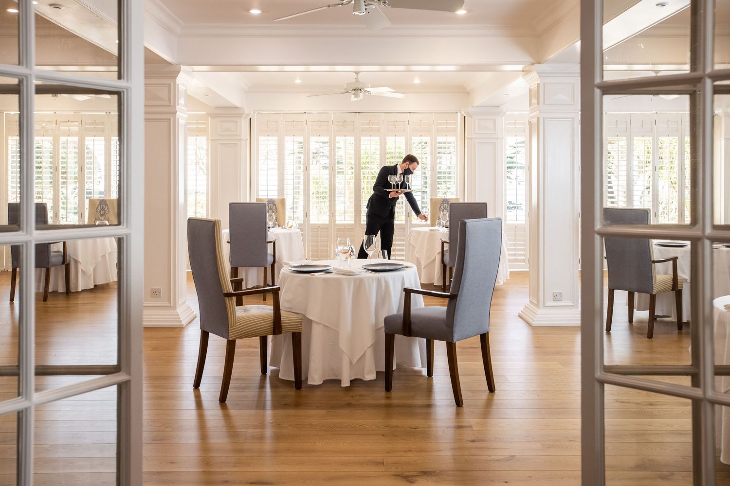 Elegant white dining room interior with large windows and modern furniture.
