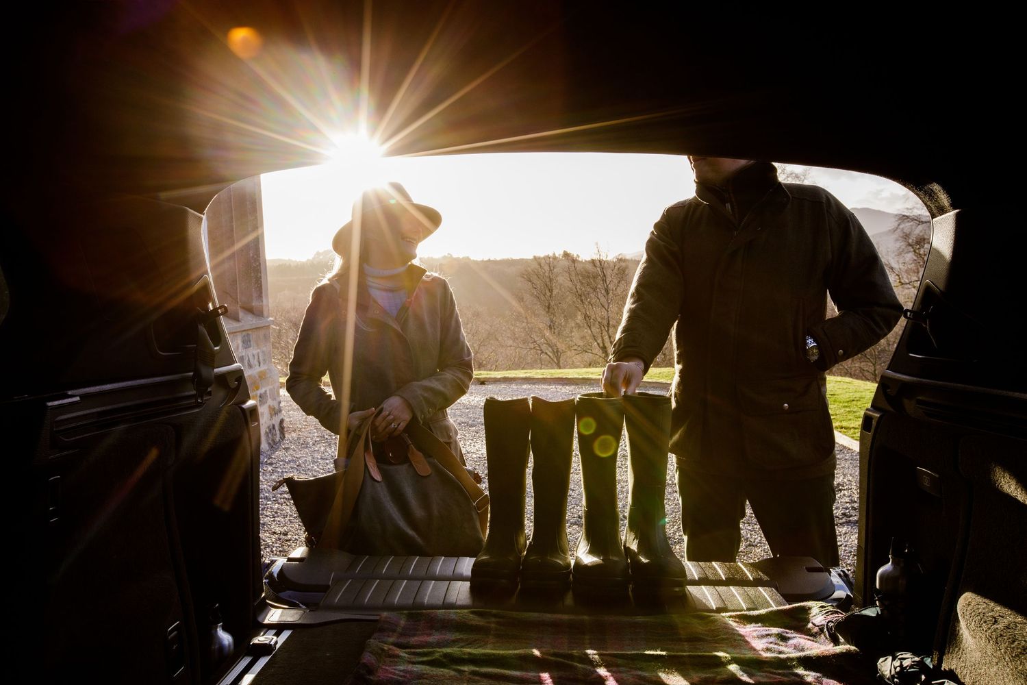 Silhouettes of people gathered at sunset with dramatic sunburst through trees.