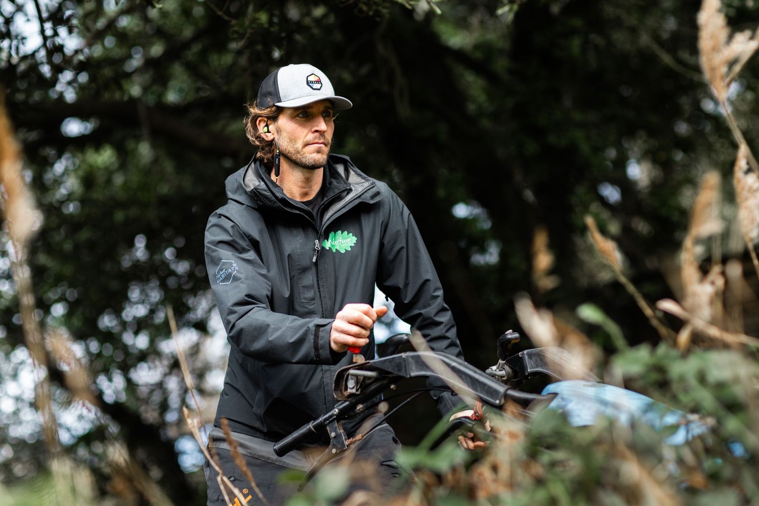 Mountain biker in grey hoodie adjusting equipment on trail.