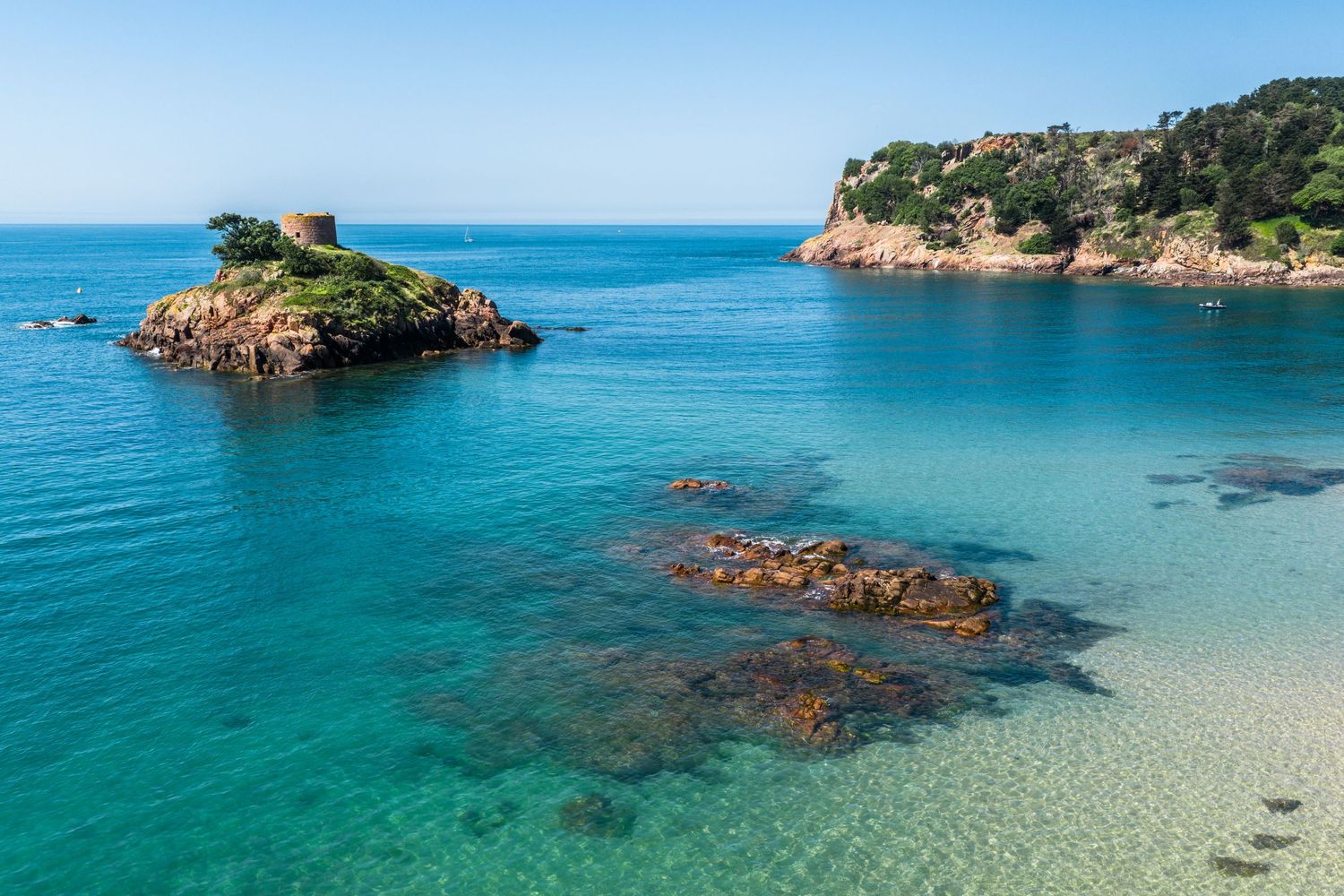 Panoramic view of pristine beach cove with turquoise waters and rocky formations.