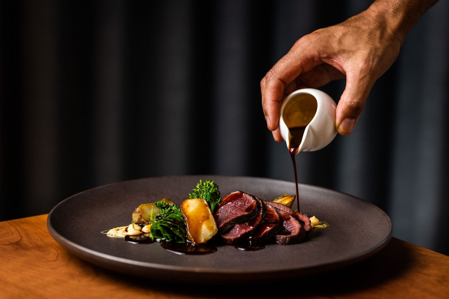 Culinary presentation featuring colorful vegetables and sauces on dark plates.