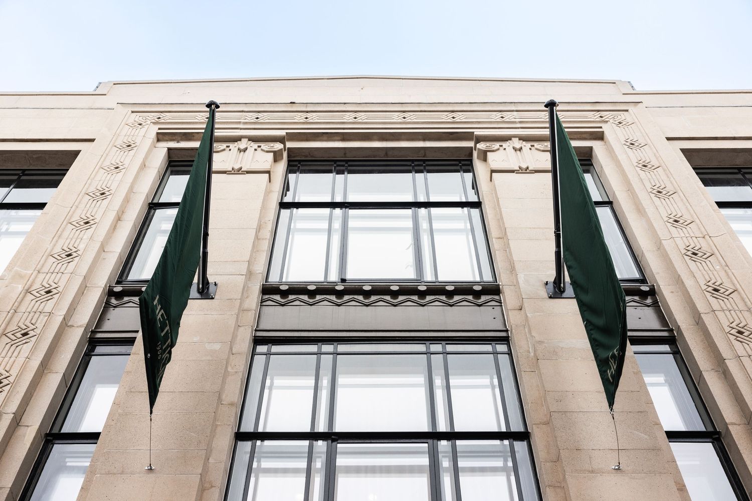 Classical stone architecture detail of a luxury retail storefront with tall windows.