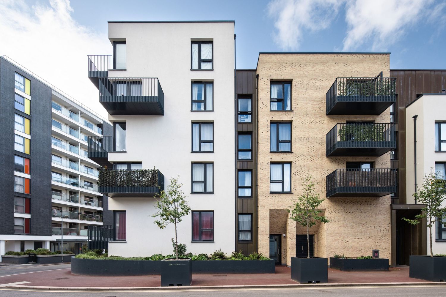 Contemporary apartment building with contrasting white and tan exterior featuring staggered balconies.