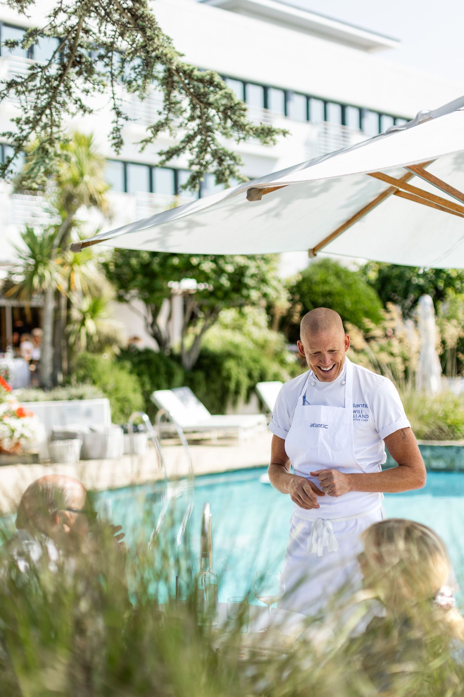 Outdoor culinary preparation area with pool and tropical landscaping visible in background.