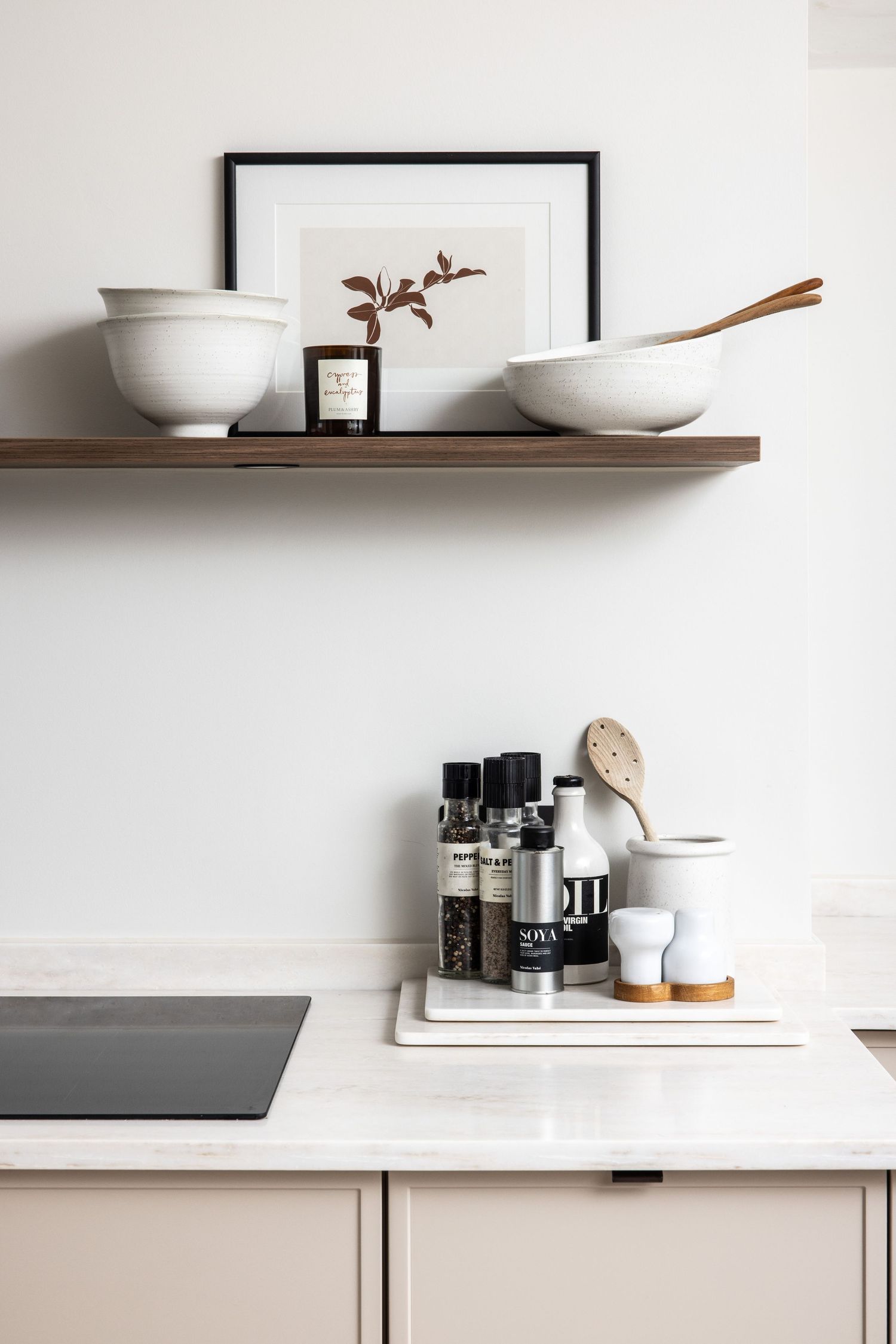 Minimalist white kitchen countertop with modern accessories and floating shelves.
