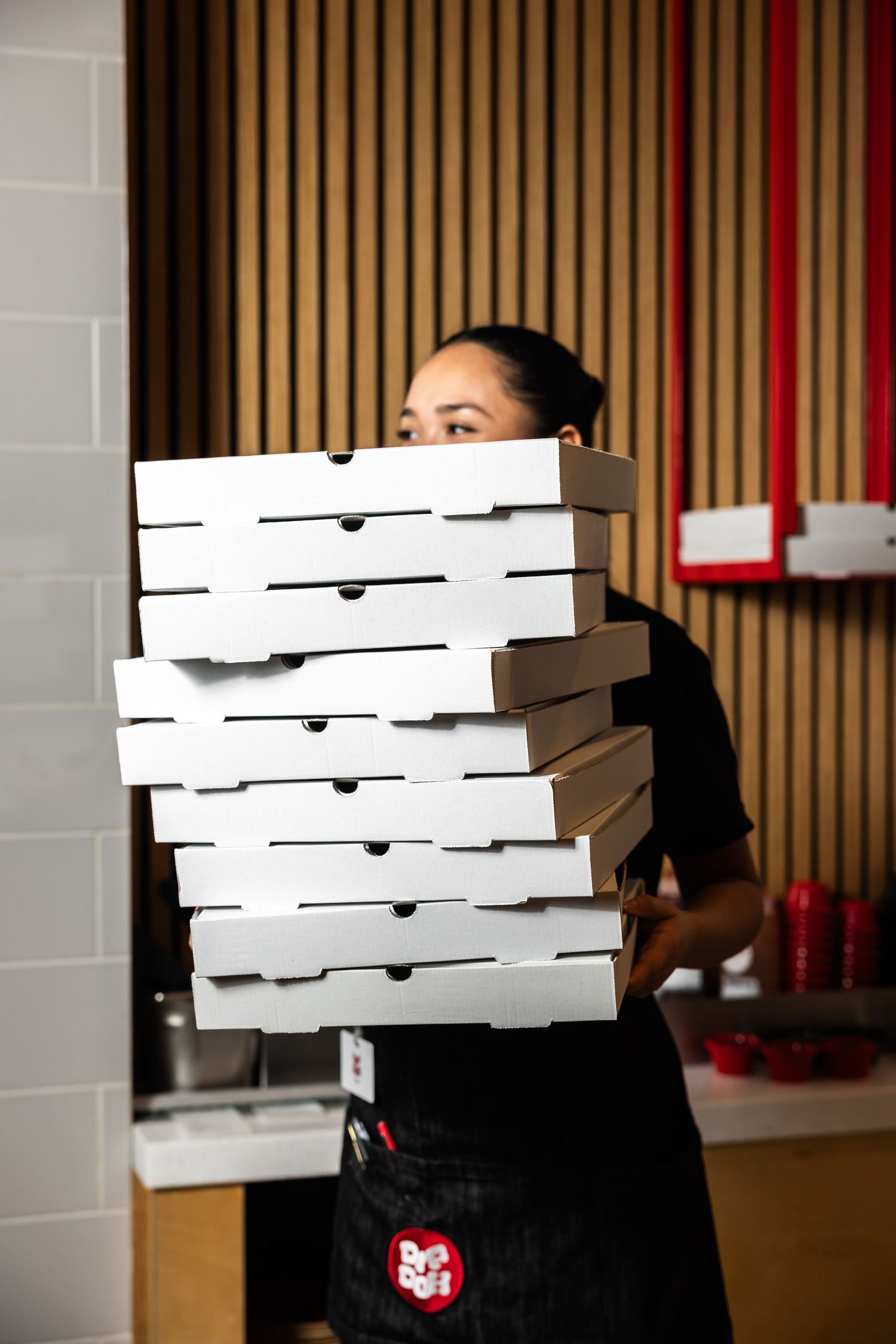 Stack of white pizza delivery boxes being carried in a restaurant.