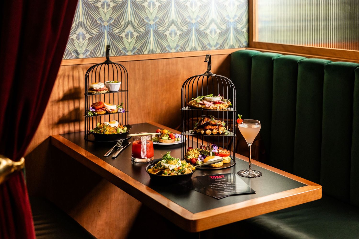 Elegant restaurant booth with afternoon tea service presented in decorative birdcage stands.