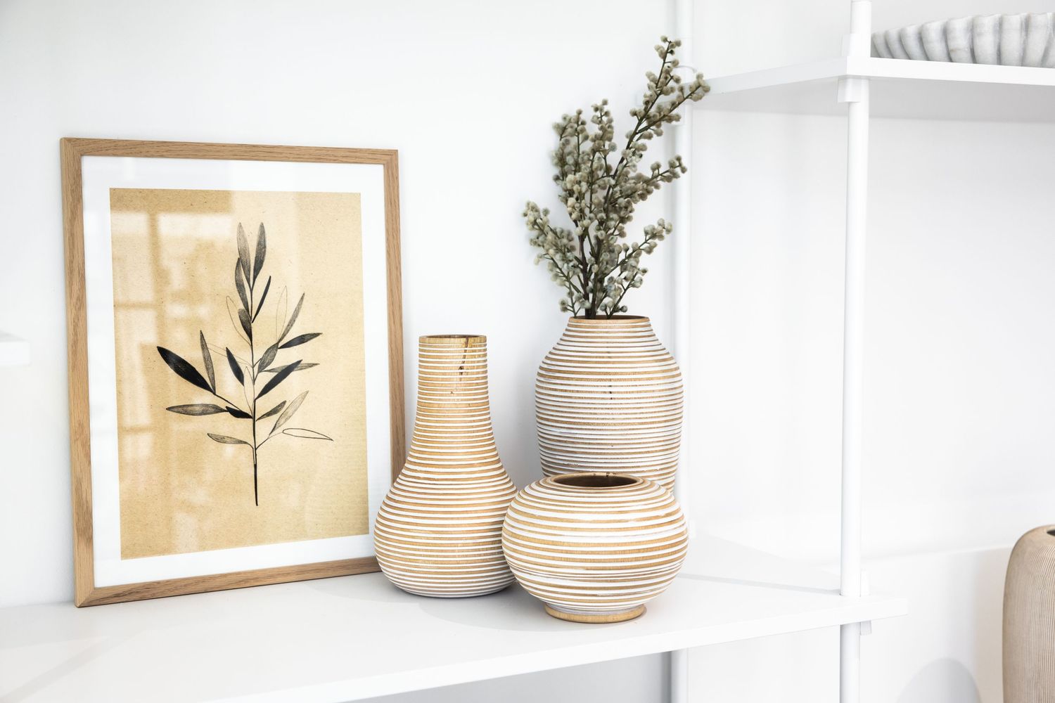 White shelving unit with natural woven baskets and botanical artwork.