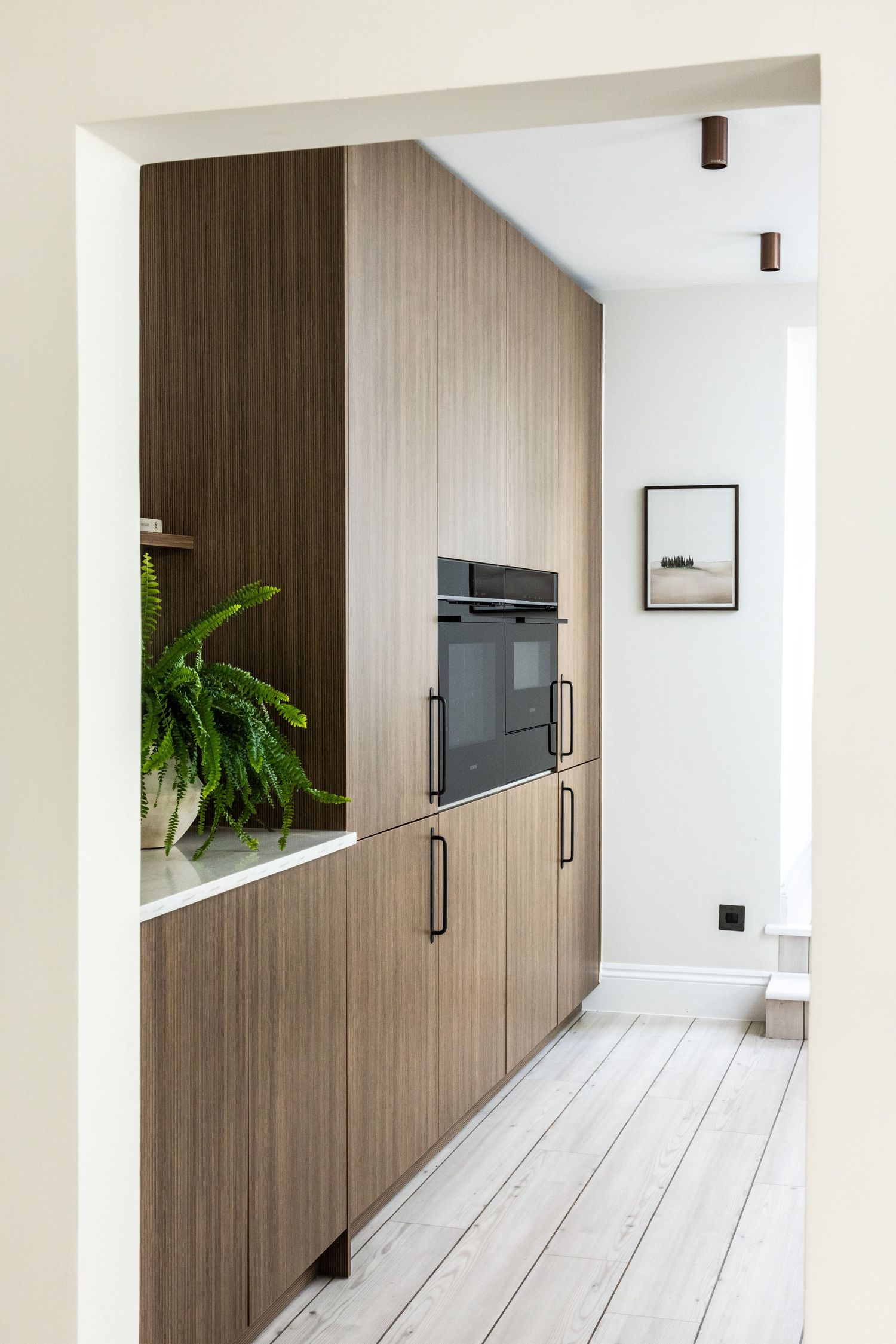 Contemporary hallway with floor-to-ceiling wood paneling and white painted floors.