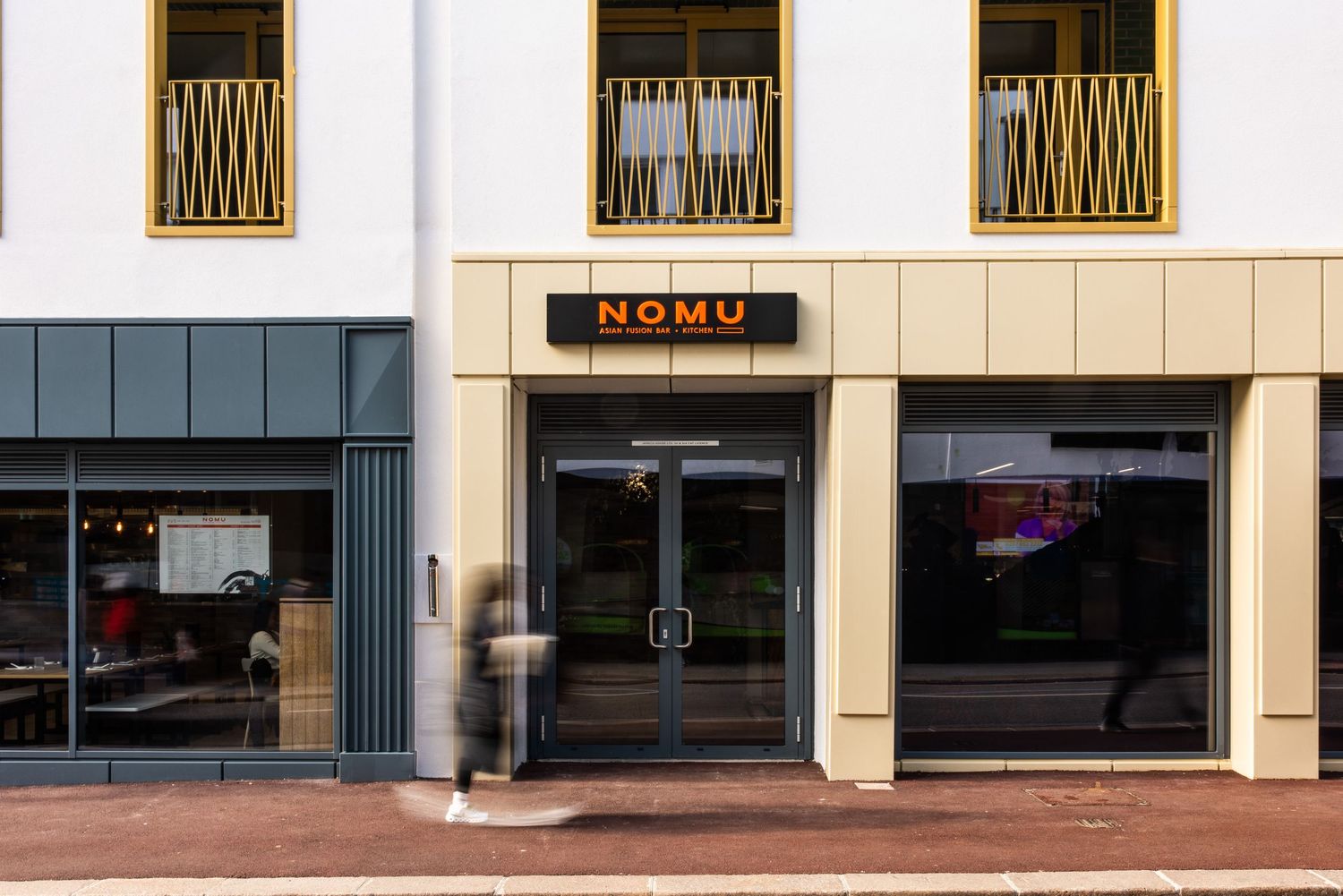 Storefront entrance of Nomu restaurant with modern architectural details and glass windows.