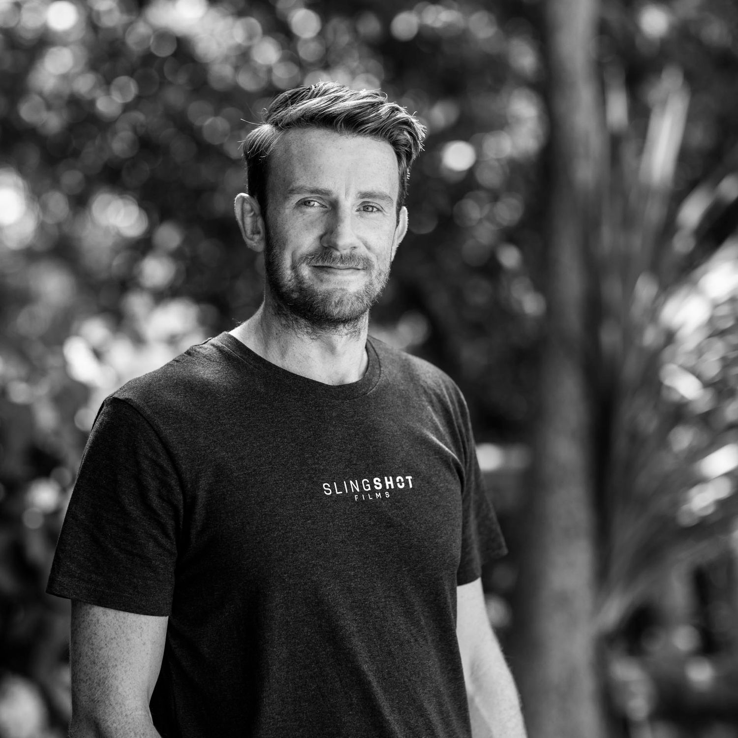 Black and white portrait of man in casual t-shirt outdoors.