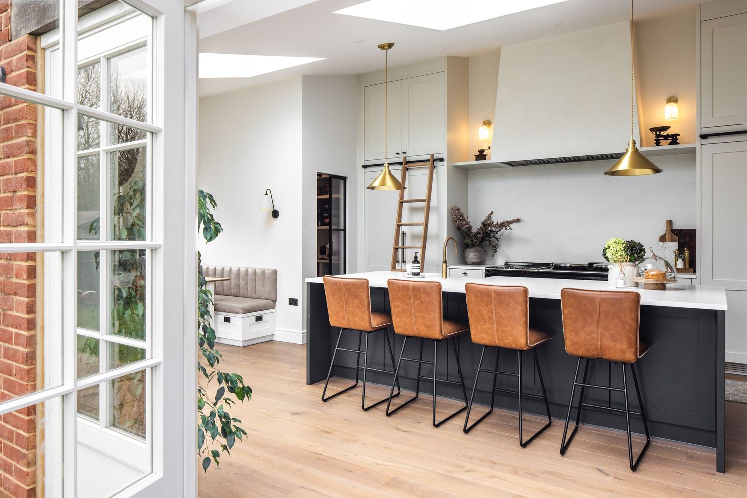 Modern kitchen featuring black island with leather barstools and French doors opening to exterior.