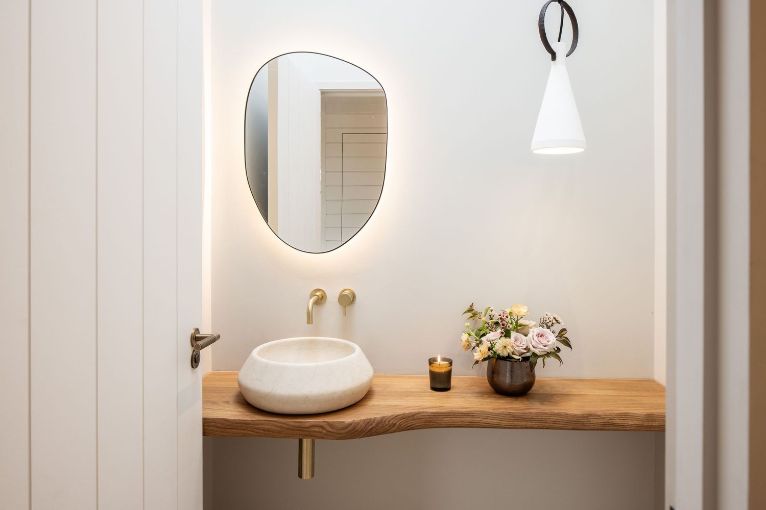 Minimalist bathroom interior with round mirror, wooden countertop, and white vessel sink.