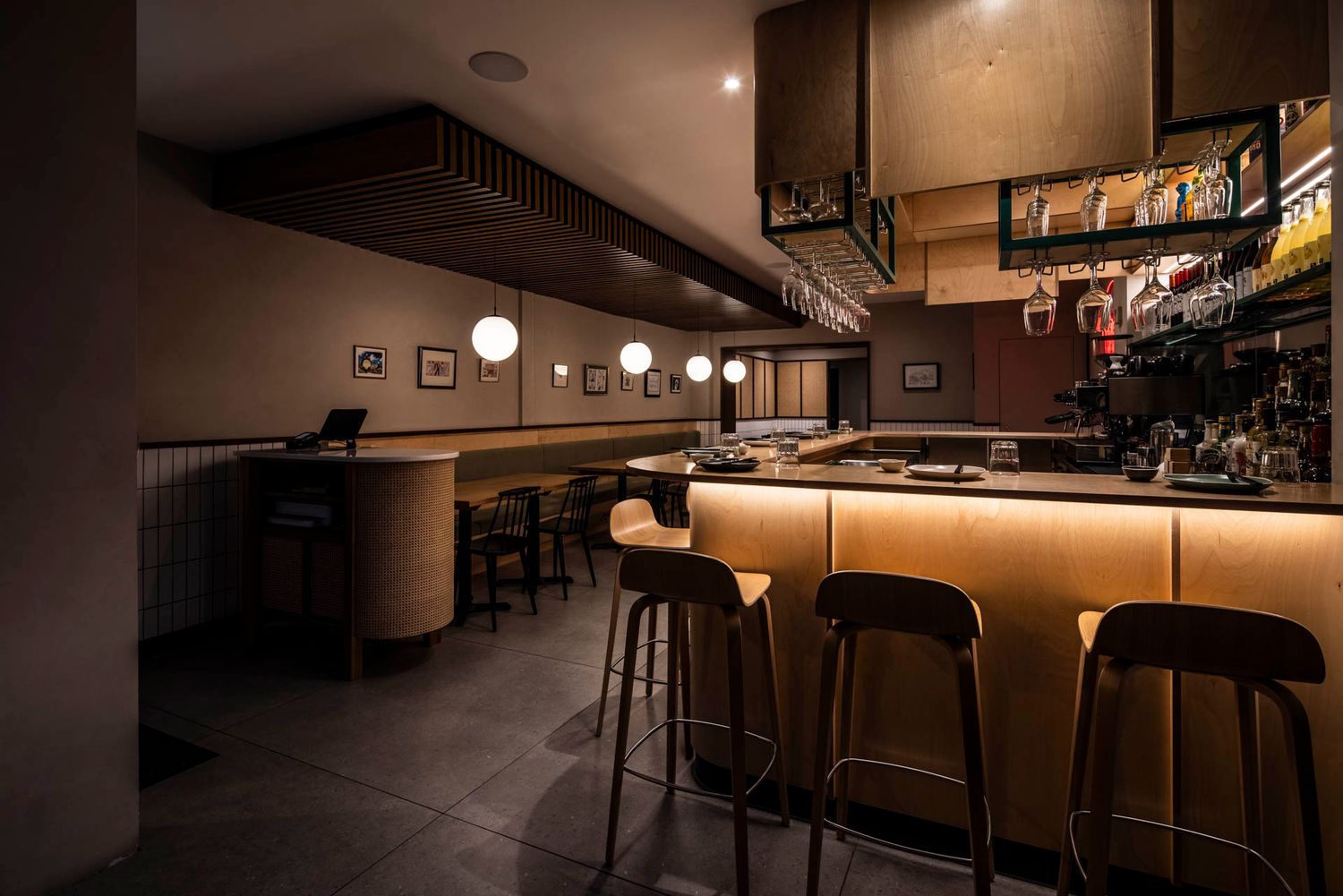 Modern bar interior with illuminated counter and industrial-style ceiling design.