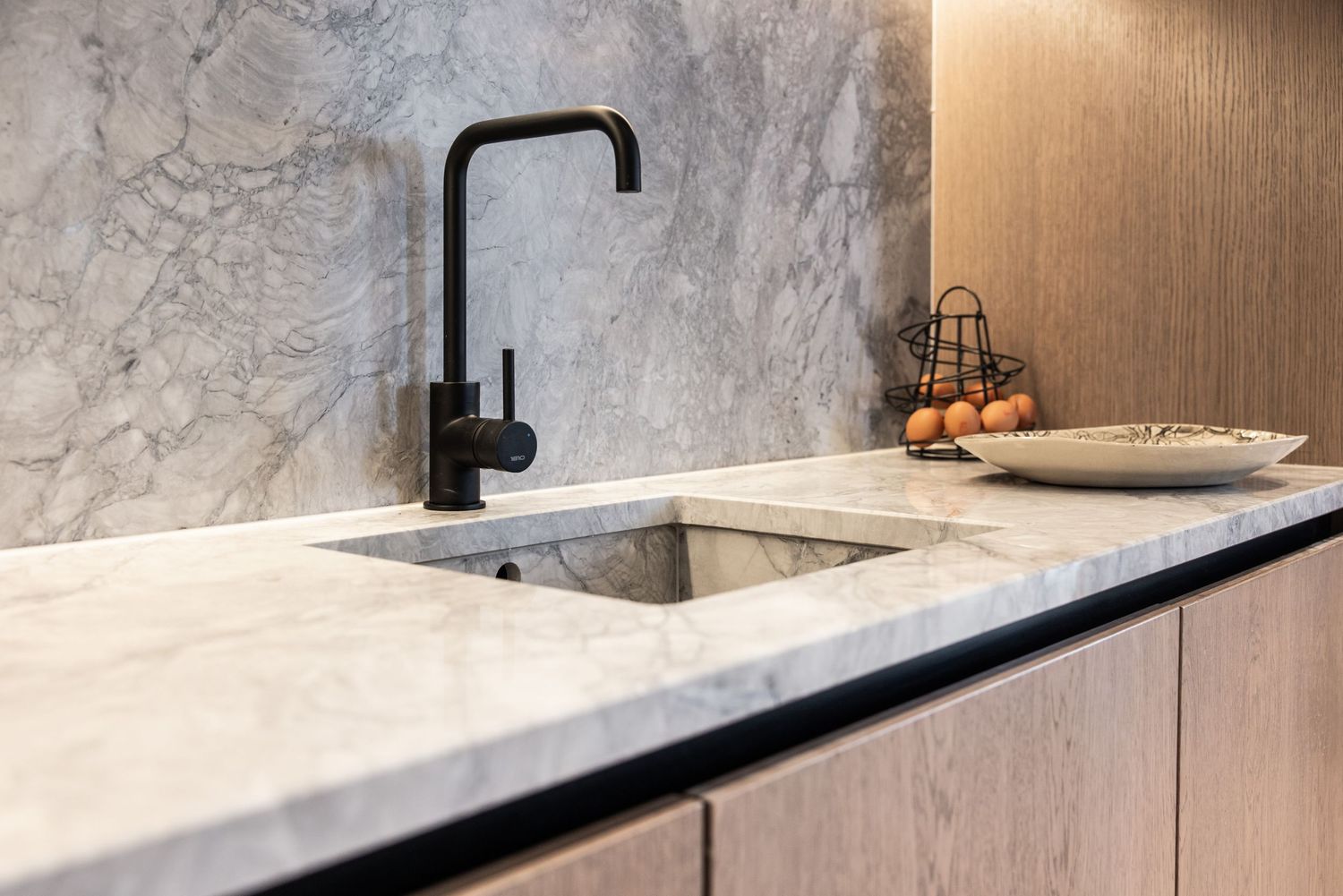 Luxury kitchen interior with marble countertops and black fixtures in minimalist design.