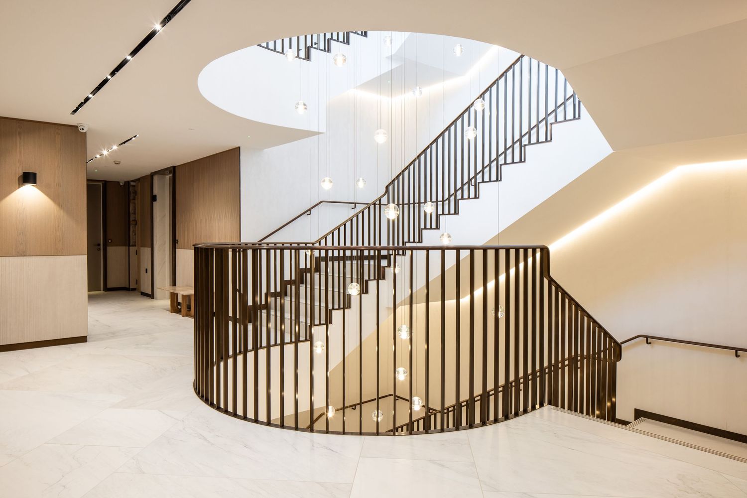 Elegant curved staircase with metal railings and natural light from above in modern building interior.