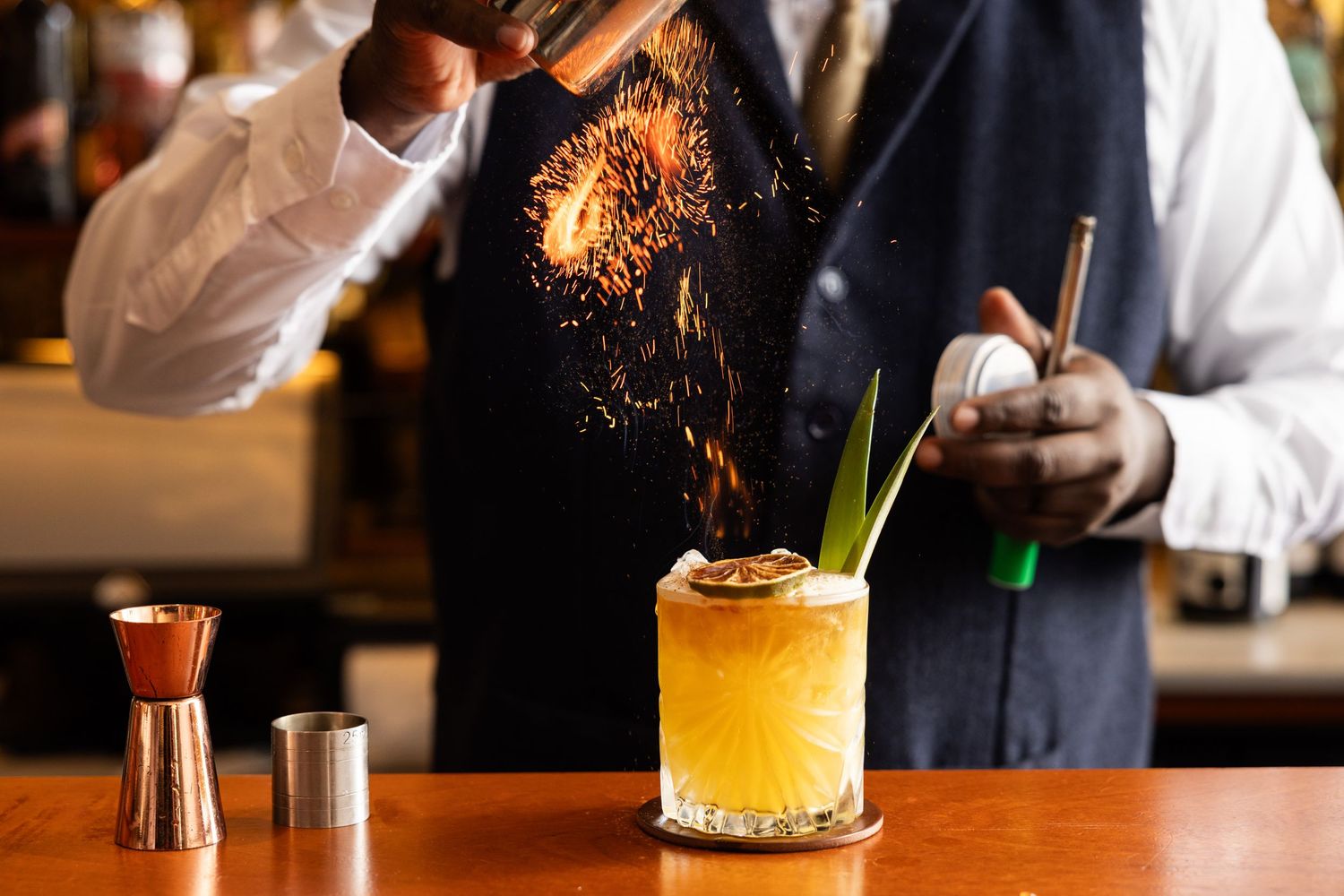 Bartender crafting cocktails with dramatic flame and smoke effects.