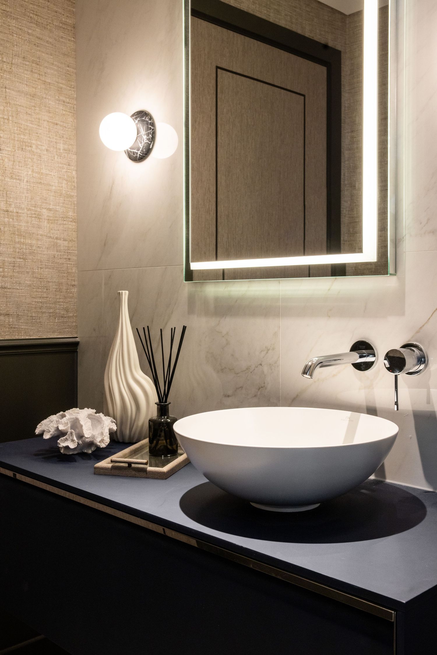 Contemporary bathroom vanity with vessel sink, backlit mirror, and minimalist design elements.
