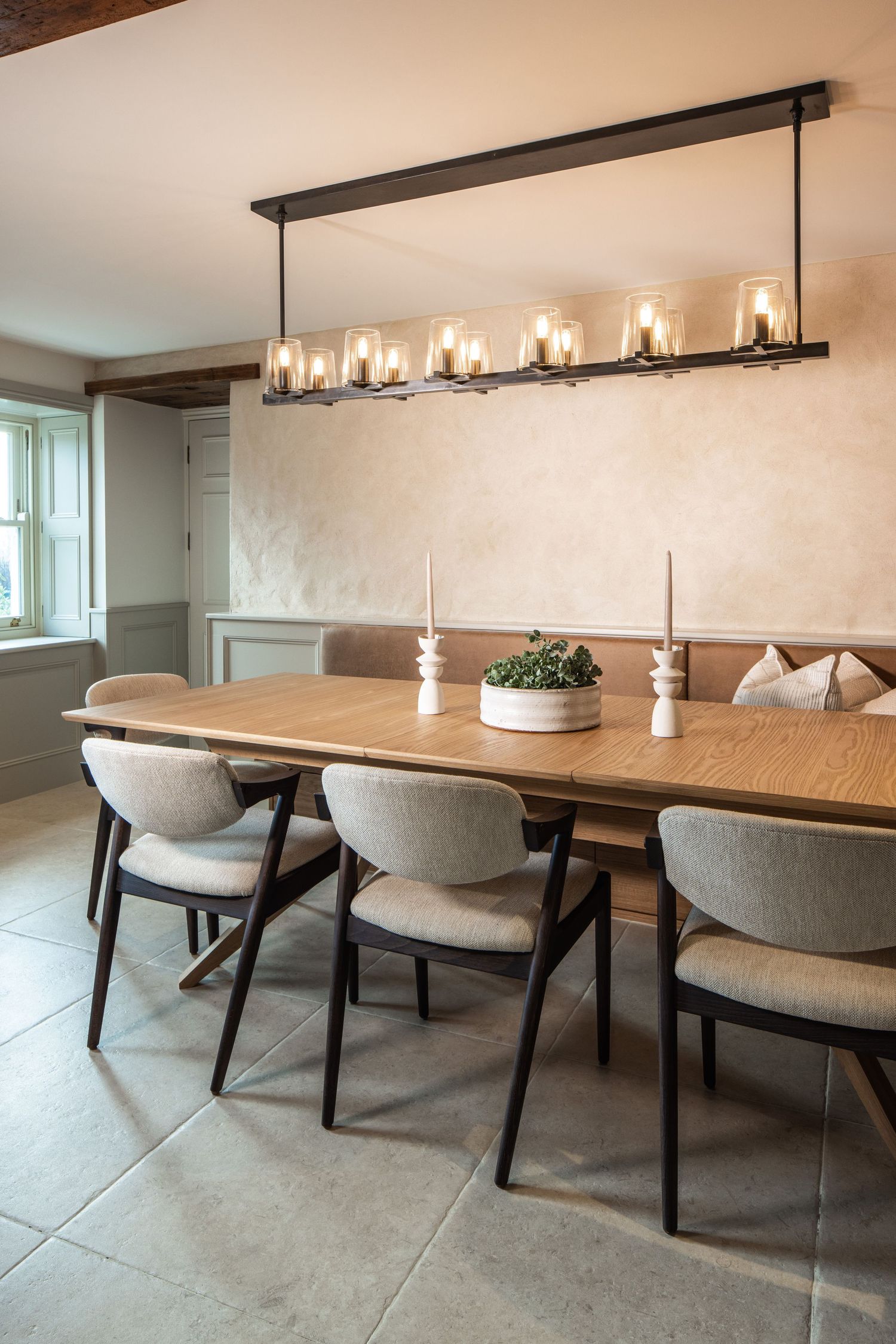 Modern dining room featuring long wooden table with gray chairs and linear pendant lighting.