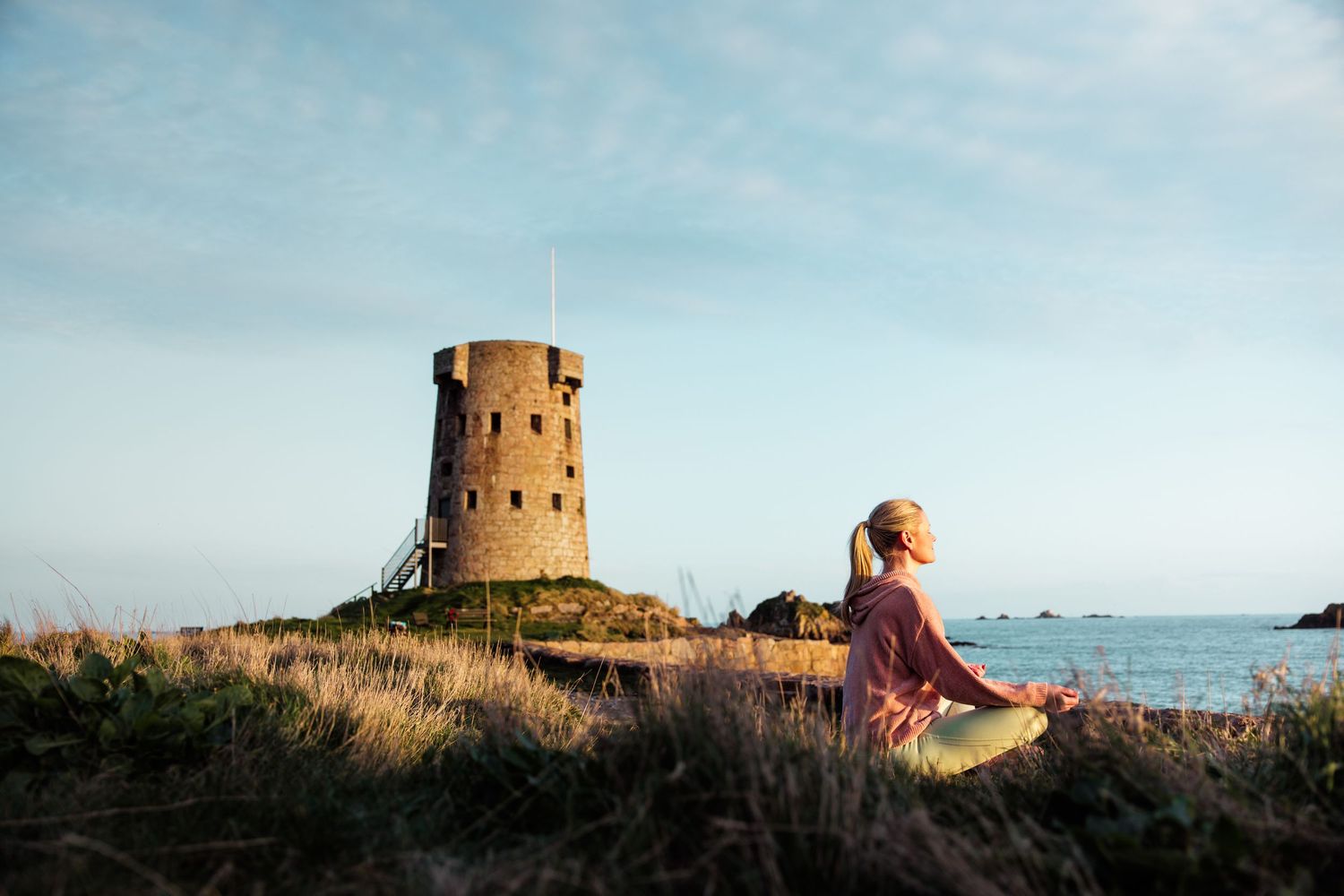 Historic stone tower overlooking coastal waters with grassy foreground.