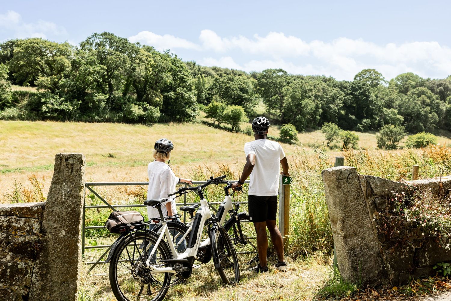 Stone wall bordering a countryside trail with cyclists enjoying the scenic view.