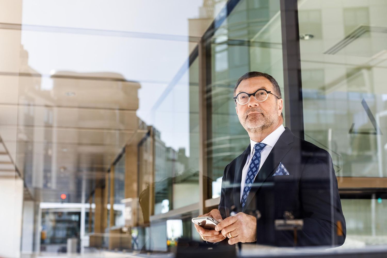 Professional in business attire standing in front of modern glass office building.