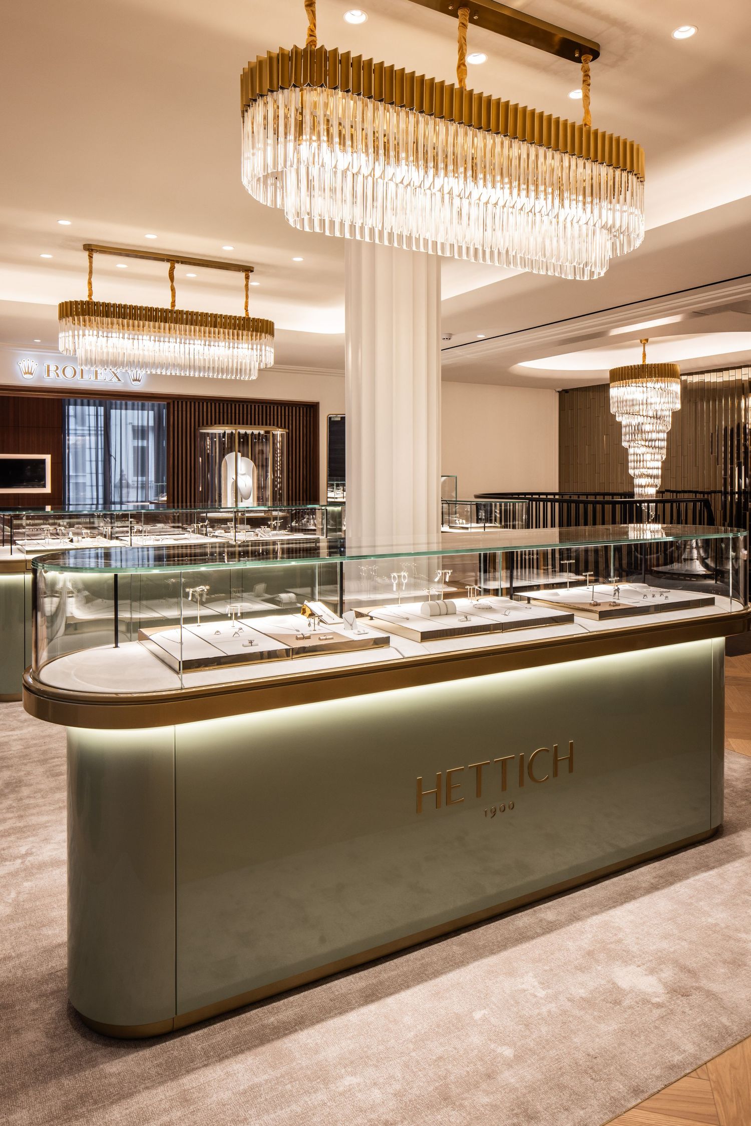 Luxury retail space with crystal chandeliers and curved display cases for jewelry.