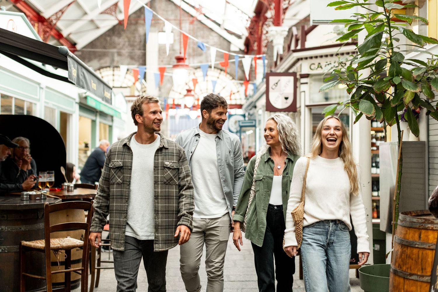 Friends enjoying a casual outing at a trendy indoor market with festive red decorations overhead.