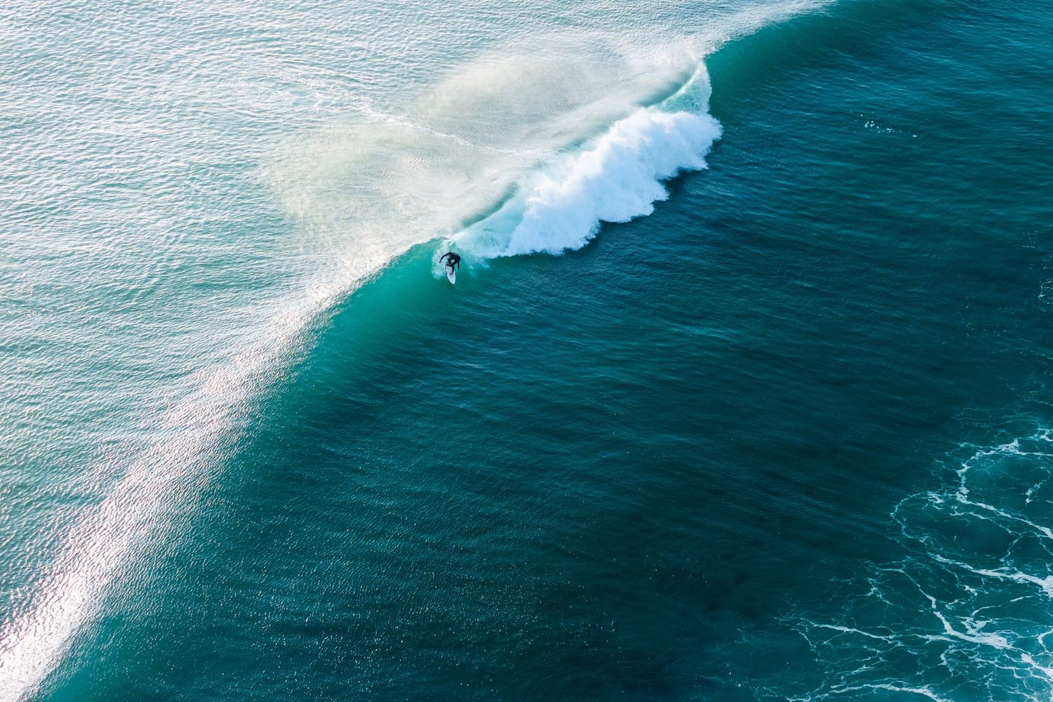 Aerial view of turquoise ocean waves breaking against a pristine coastline.