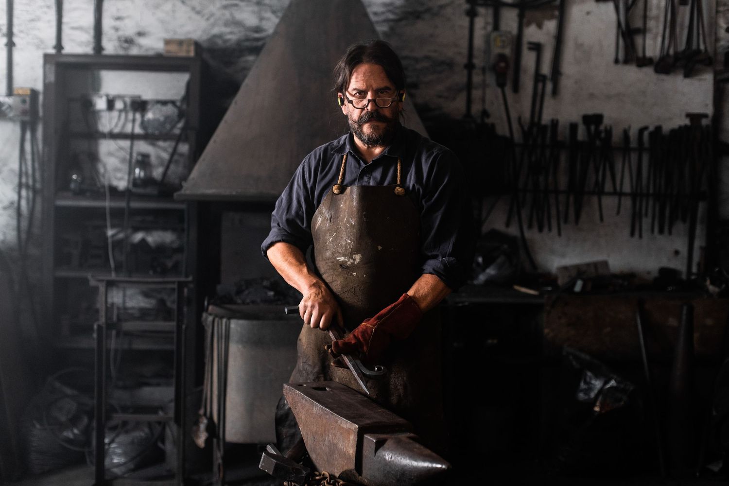 Dark industrial workshop setting with metalworking tools and equipment.