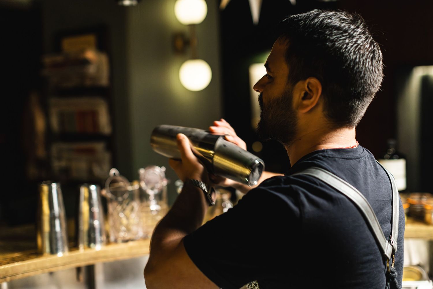 Bartender preparing cocktails at an illuminated bar counter.