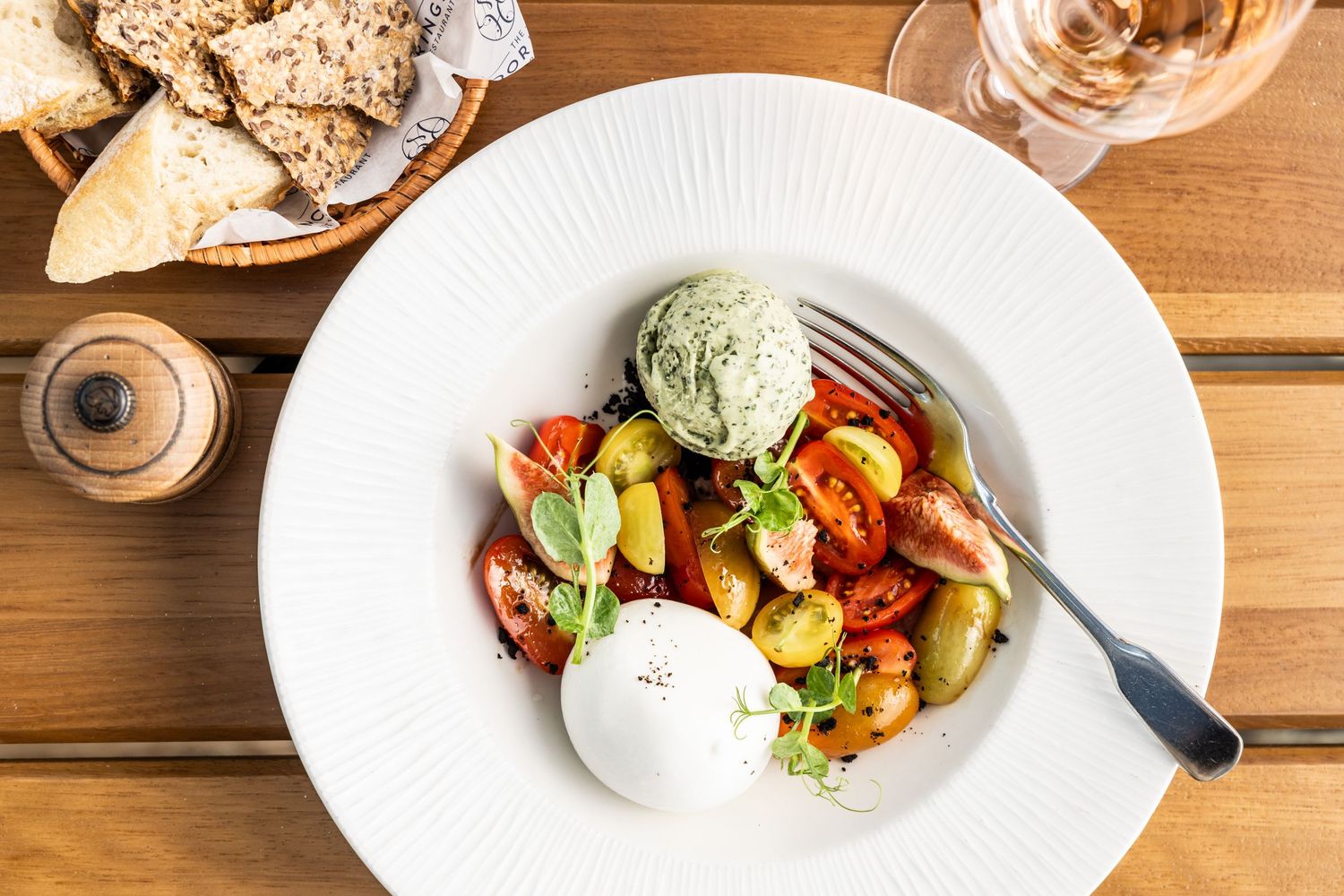Artfully plated dishes on wooden tables with colorful salads and appetizers in an upscale restaurant setting.