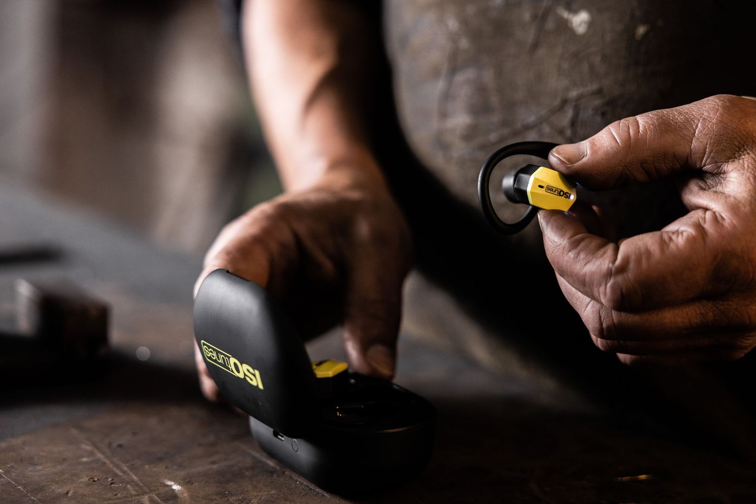 Close up of hands measuring with a black tape measure on a wooden surface.