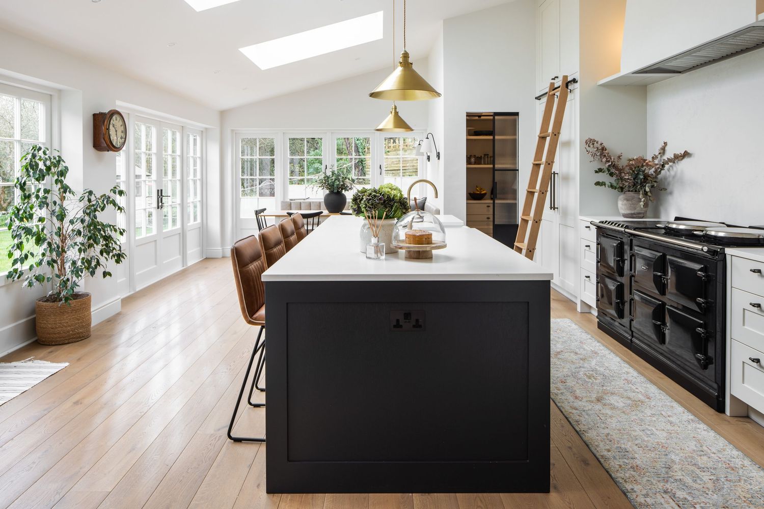 Bright kitchen with black island, leather barstools and large windows letting in natural light.