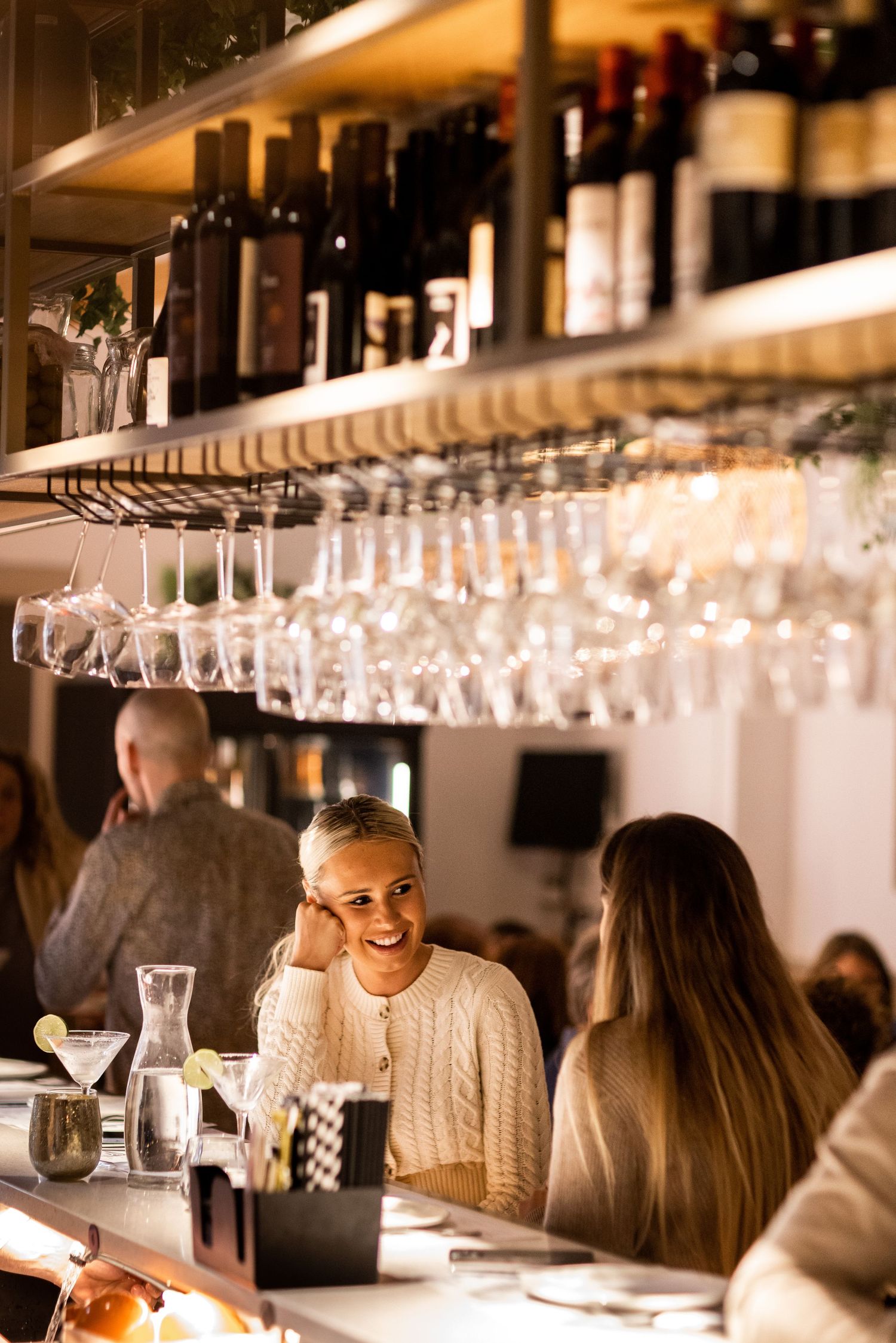 Cozy restaurant bar interior with hanging wine glasses and warm lighting.
