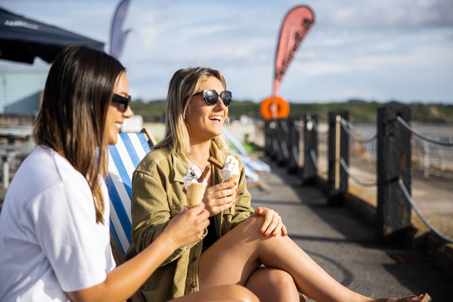 Friends enjoying drinks on outdoor deck during sunny afternoon.