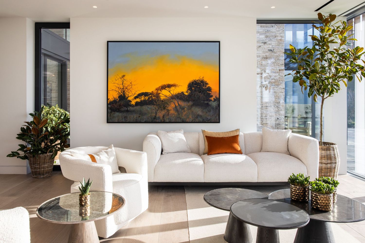 Elegant living space with white sofa, sunset artwork, and contemporary decor accents.