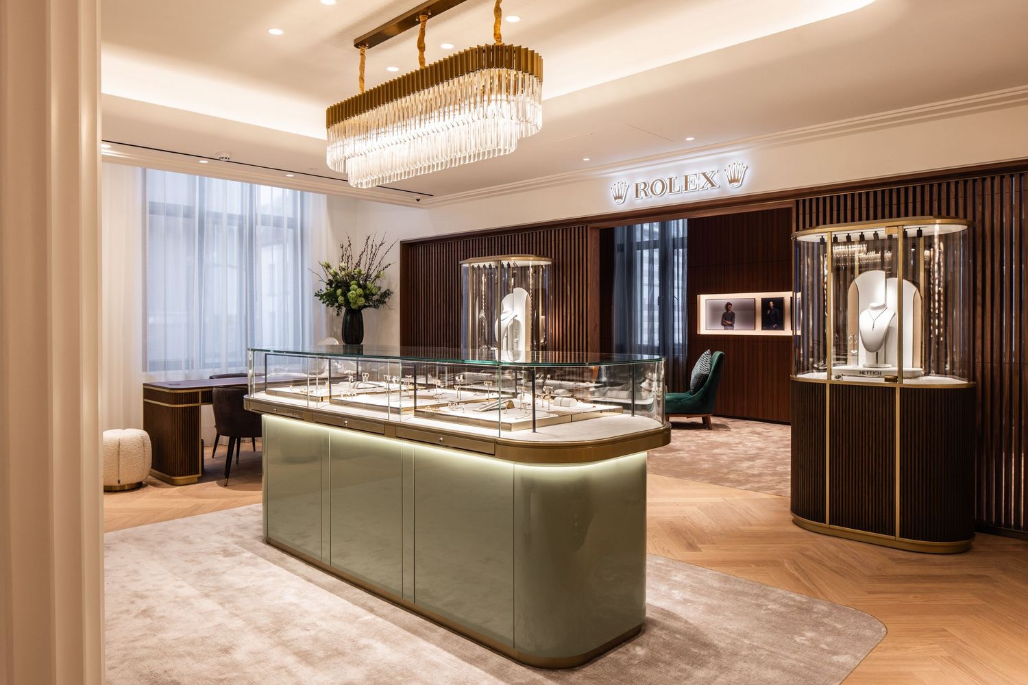 Upscale jewelry store interior with sage green display islands and crystal chandeliers.