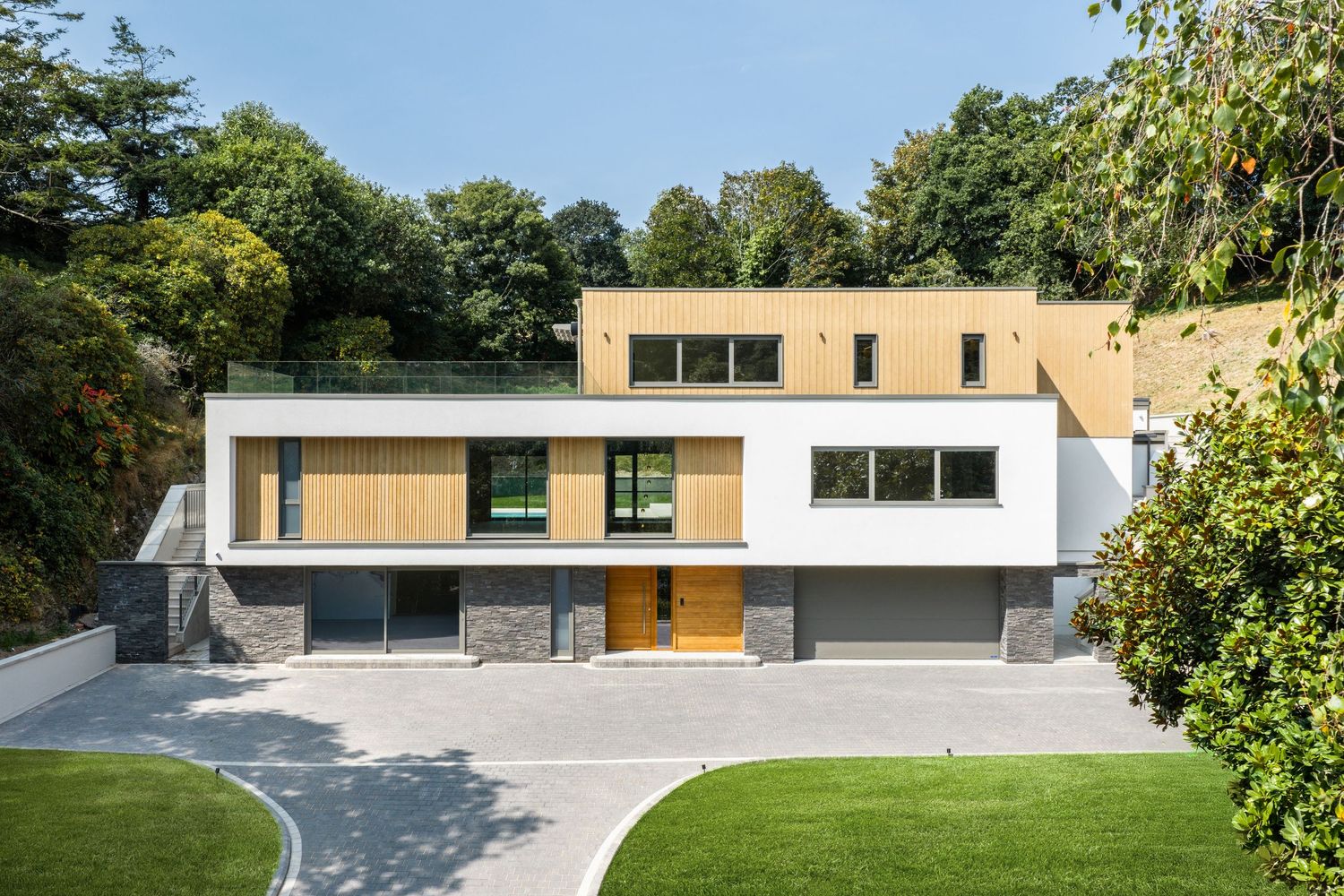 Contemporary architectural design featuring geometric shapes and large windows set against green surroundings.