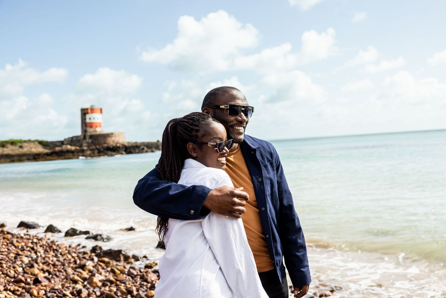 Beachside scene with couple enjoying views of lighthouse and turquoise waters.