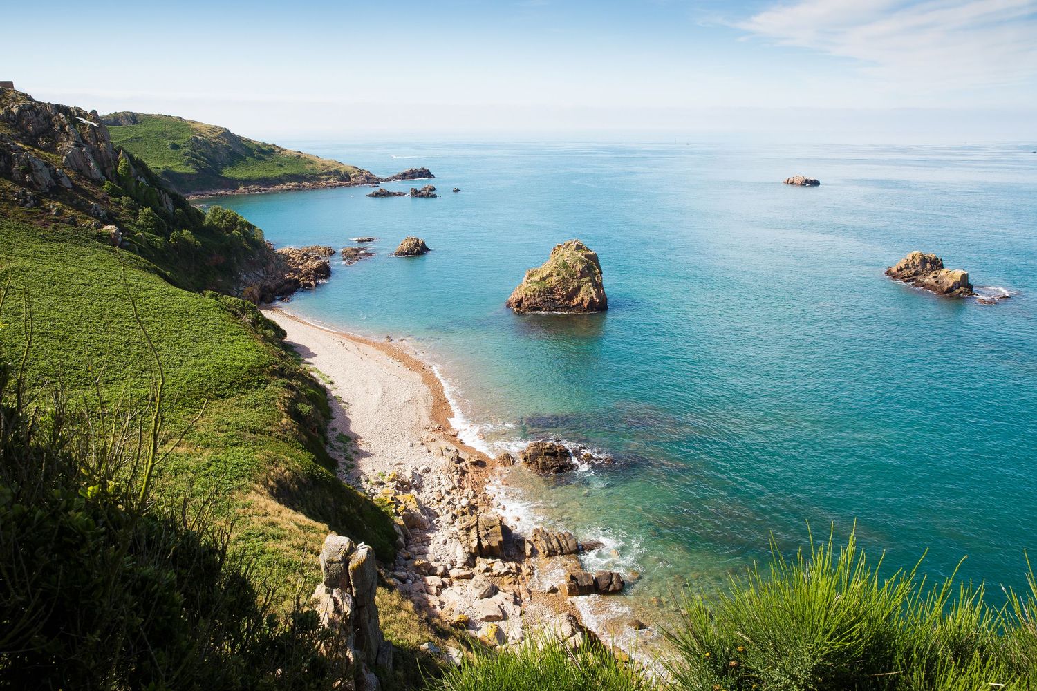 Coastal cove with turquoise waters and rocky outcrops along a scenic beach.